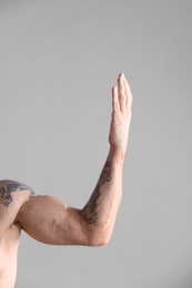 Tattooed man on grey background, closeup of arm