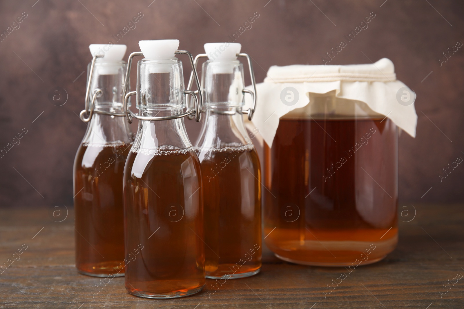 Photo of Tasty kombucha in jar and bottles on wooden table