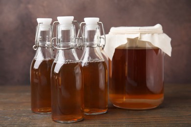 Tasty kombucha in jar and bottles on wooden table