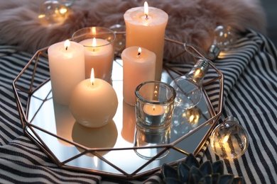 Photo of Tray with burning candles on striped fabric