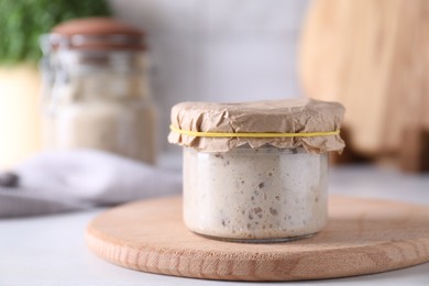 Photo of Sourdough starter in glass jar on table, closeup. Space for text