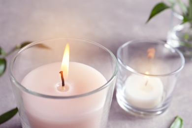 Photo of Burning wax candle in glass on table, closeup