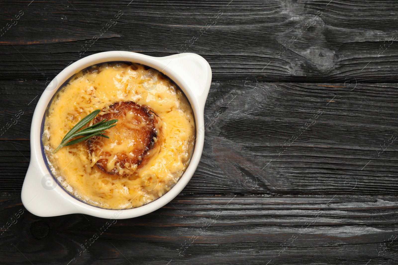 Photo of Tasty homemade french onion soup on black wooden table, top view. Space for text