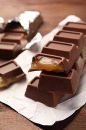 Photo of Tasty chocolate bars on wooden table, closeup