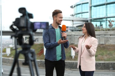 Young journalist interviewing businesswoman on city street