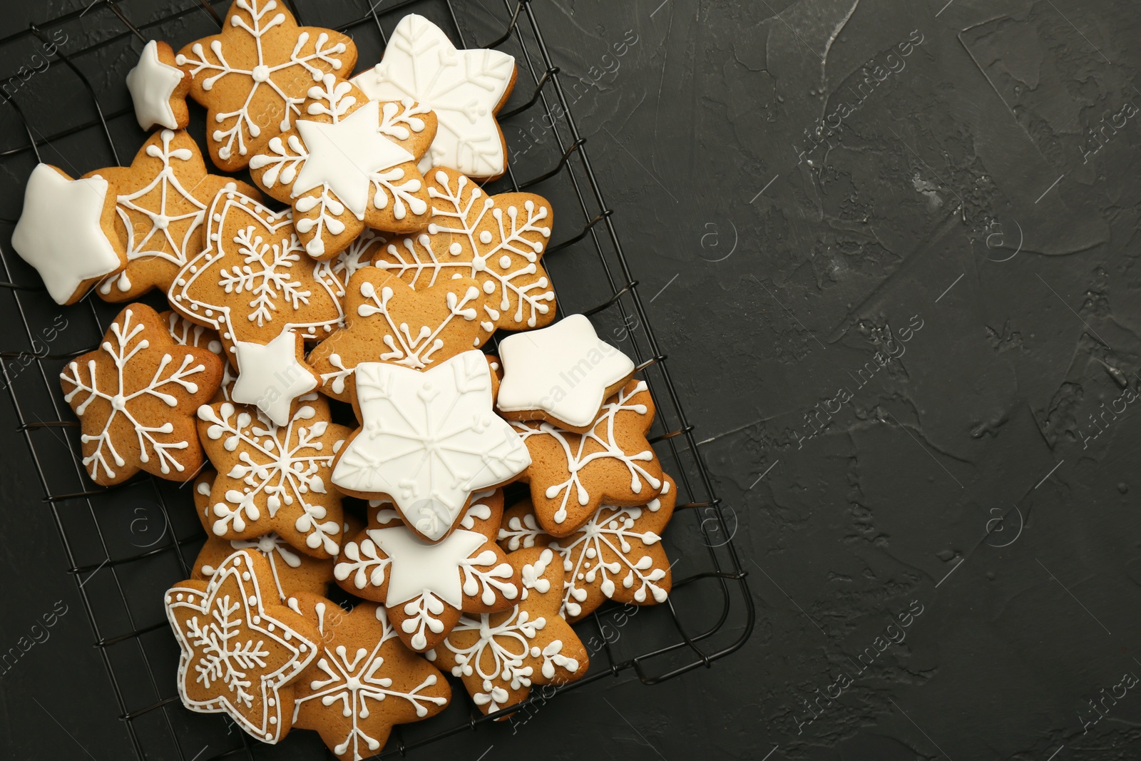 Photo of Tasty Christmas cookies with icing on black table, top view. Space for text