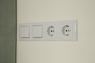 Light switches and power sockets on white wall indoors