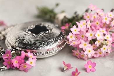 Photo of Beautiful Forget-me-not flowers and pocket watch on grey table, closeup