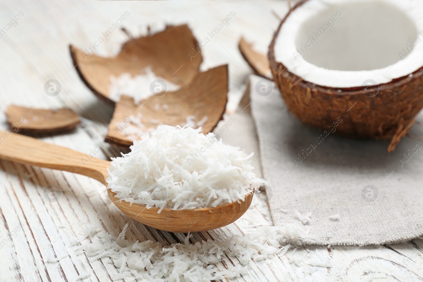 Photo of Wooden spoon with fresh coconut flakes on wooden background