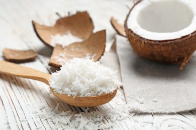 Wooden spoon with fresh coconut flakes on wooden background