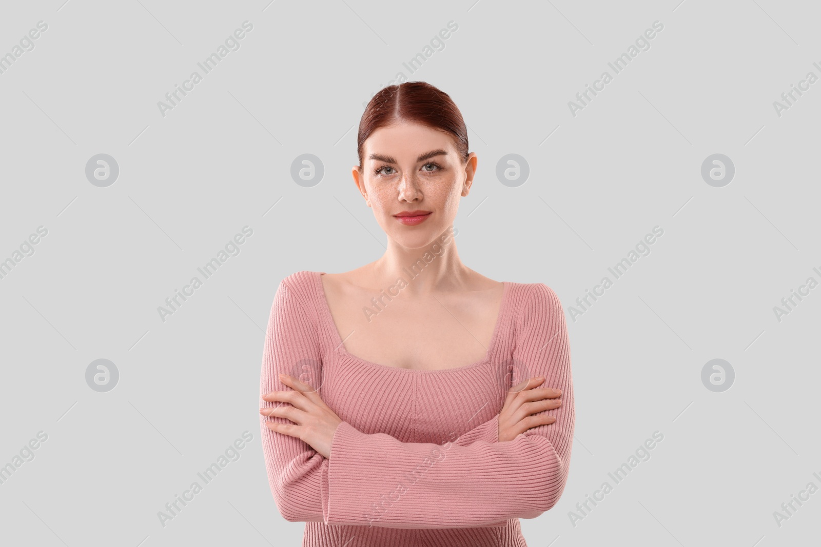 Photo of Portrait of beautiful woman with crossed arms on light background