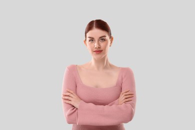 Portrait of beautiful woman with crossed arms on light background