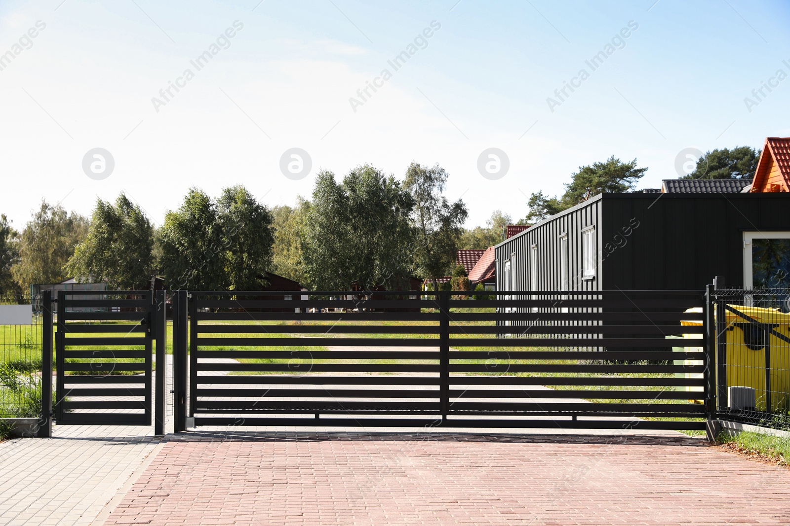 Photo of Gray metal gates near beautiful trees and houses