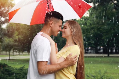 Photo of Lovely couple with umbrella walking under rain in park