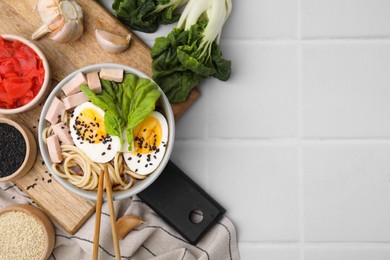 Photo of Bowl of delicious ramen with meat, egg and ingredients on white tiled table, flat lay with space for text. Noodle soup