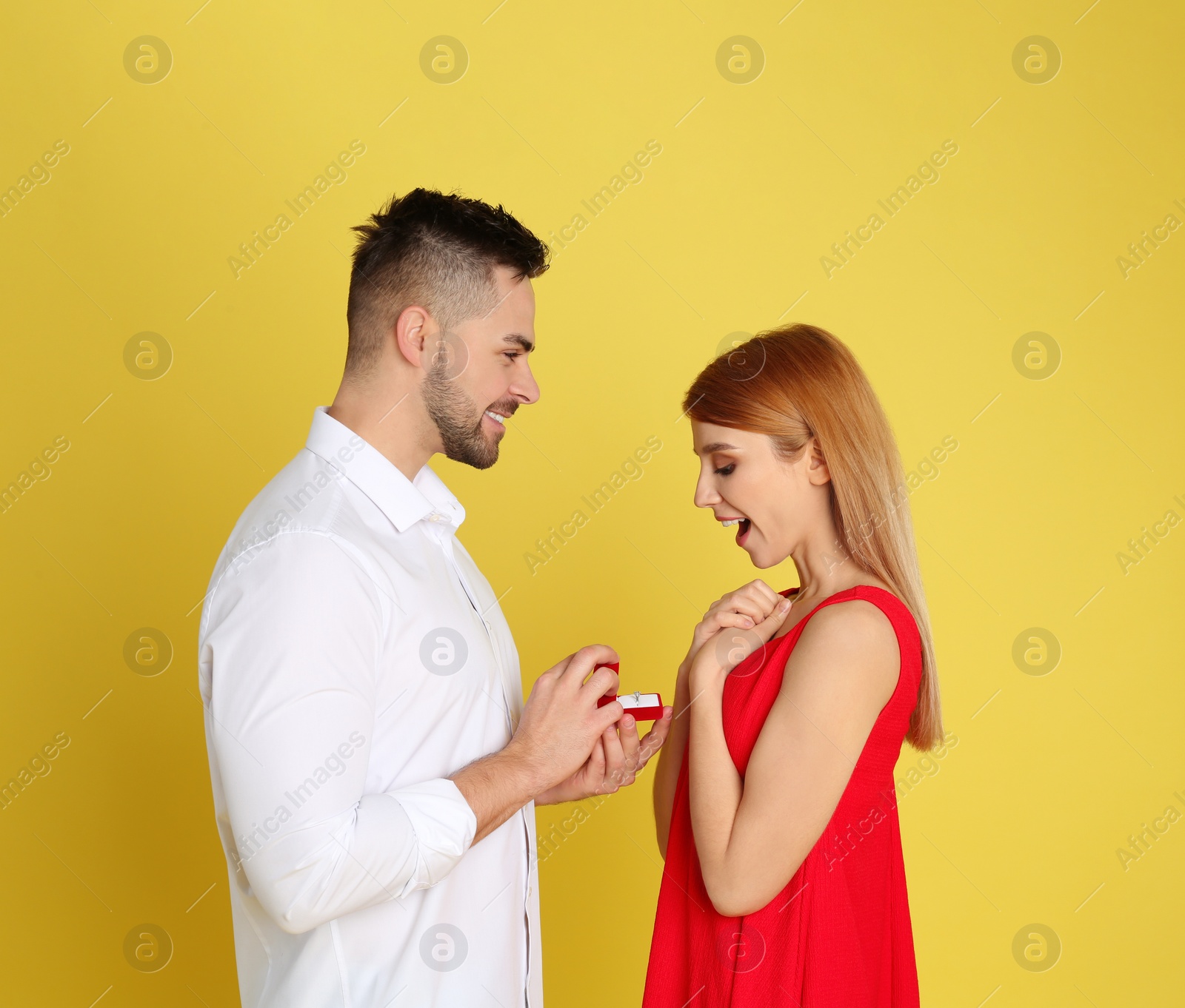 Photo of Man with engagement ring making marriage proposal to girlfriend on yellow background