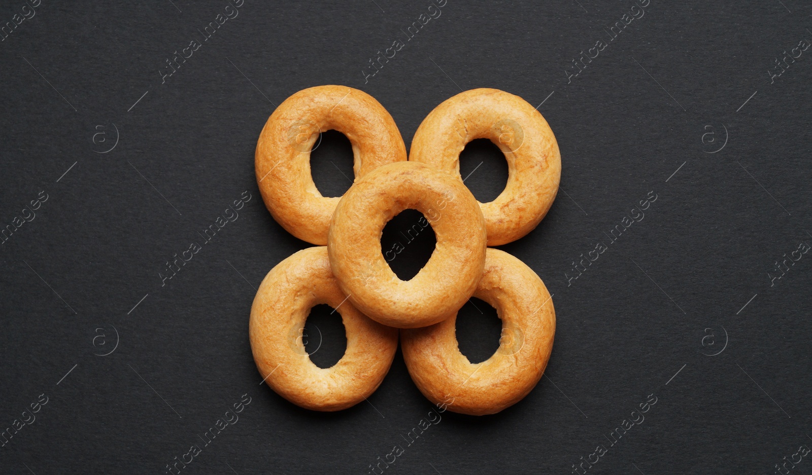 Photo of Tasty dry bagels (sushki) on black background, flat lay