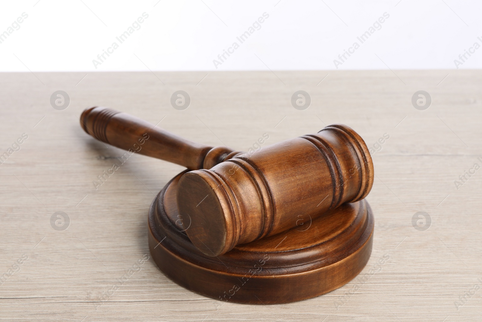 Photo of Wooden gavel on light table against white background