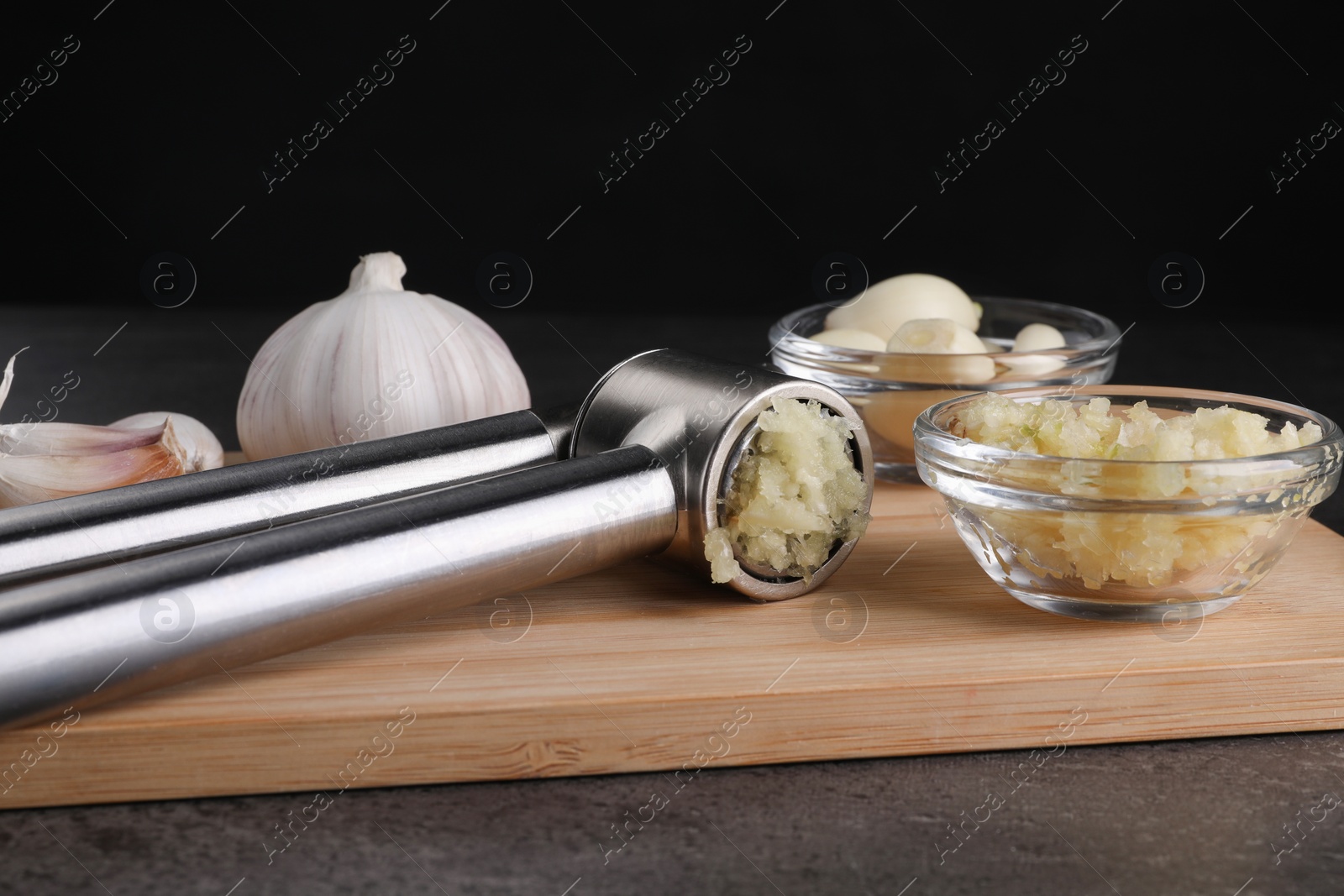 Photo of Garlic press and mince on grey table, closeup