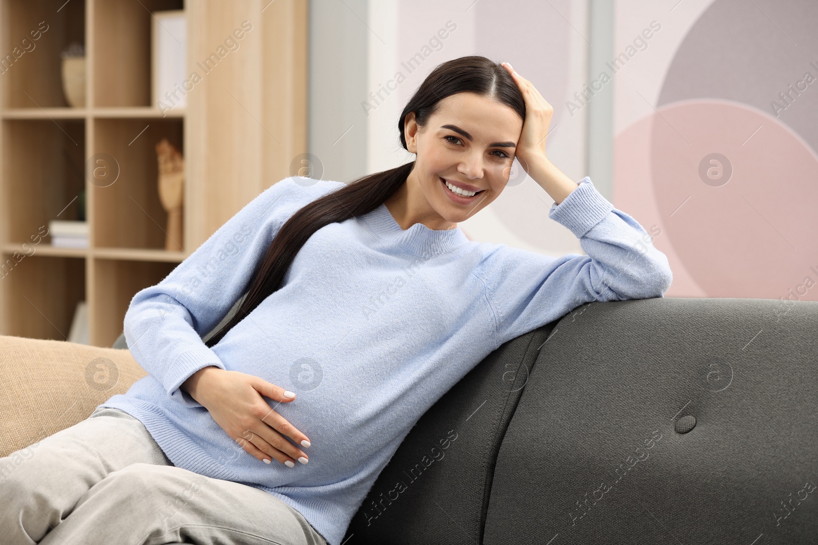 Photo of Happy pregnant woman on sofa at home