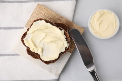 Slices of tasty bread with butter and knife on white tiled table, flat lay