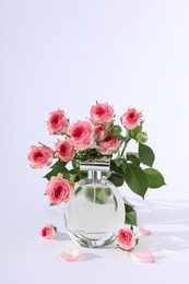 Photo of Bottle of luxury perfume and beautiful roses on white background. Floral fragrance