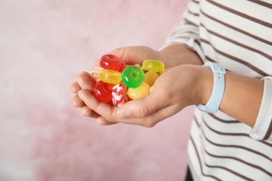 Photo of Woman holding many colorful candies on color background, closeup. Space for text