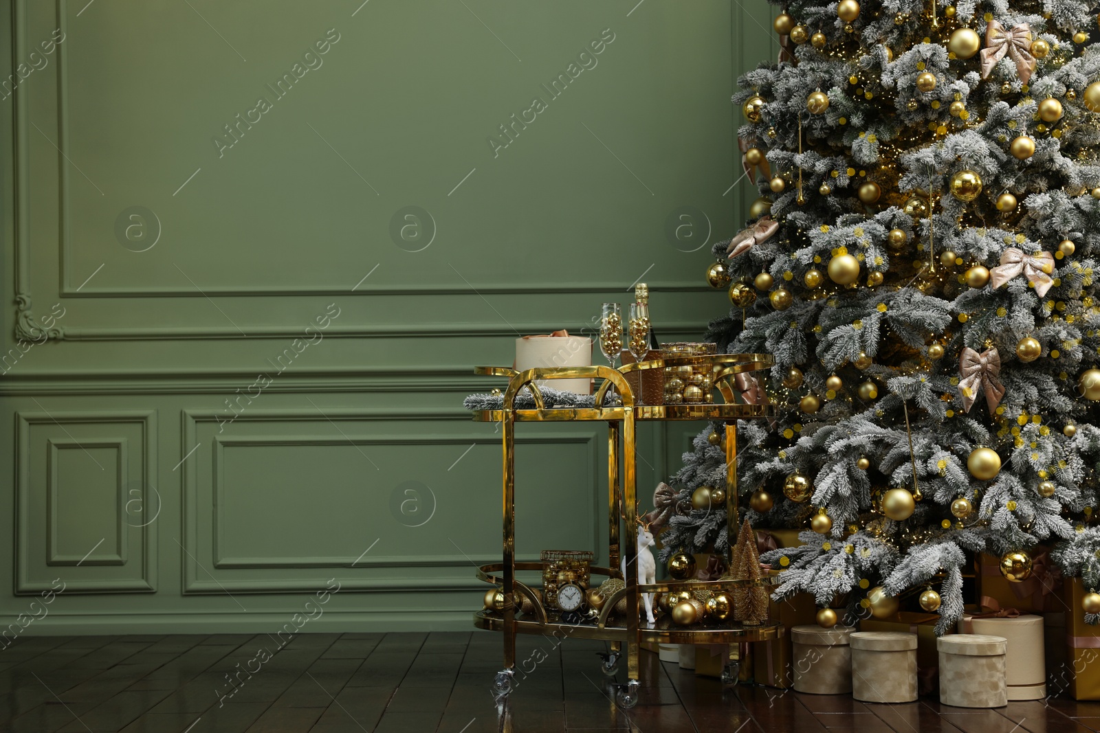 Photo of Beautiful Christmas tree, gift boxes, table and festive decor near olive wall indoors with space for text. Interior design