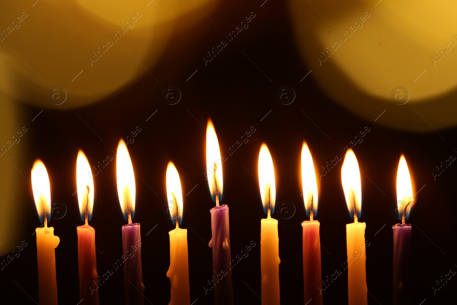 Photo of Hanukkah celebration. Burning candles on dark background with blurred lights