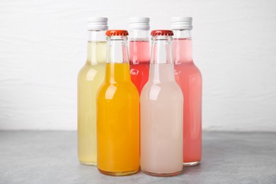 Photo of Delicious kombucha in glass bottles on grey table against white background