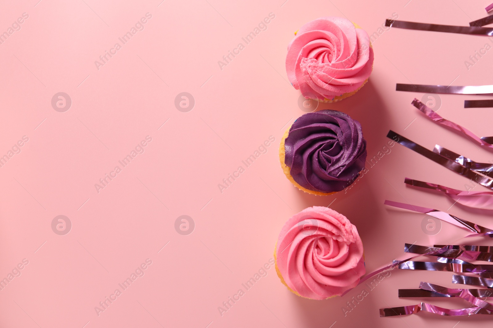 Photo of Delicious cupcakes with bright cream and confetti on pink background, flat lay. Space for text