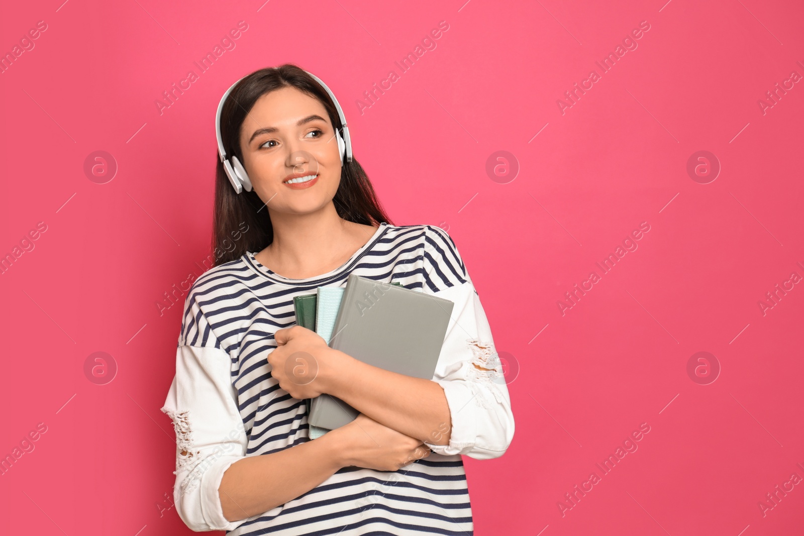 Photo of Young woman listening to audiobook on pink background. Space for text