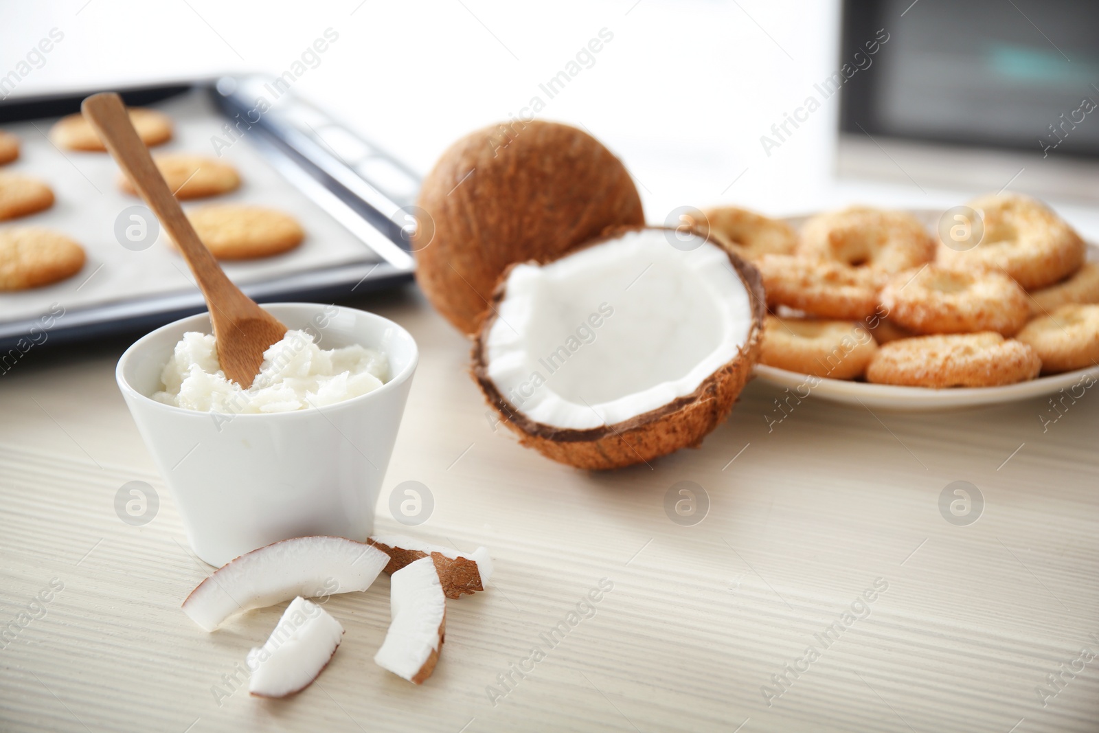 Photo of Bowl with coconut oil and nut pieces on wooden table