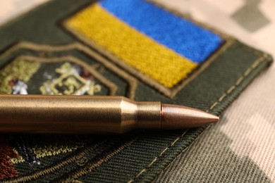 Photo of Bullet and military Ukrainian patch on pixel camouflage, closeup