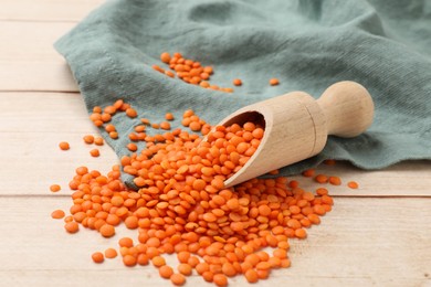 Scoop of raw lentils on wooden table, closeup