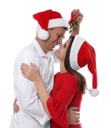 Photo of Happy couple standing under mistletoe bunch on white background