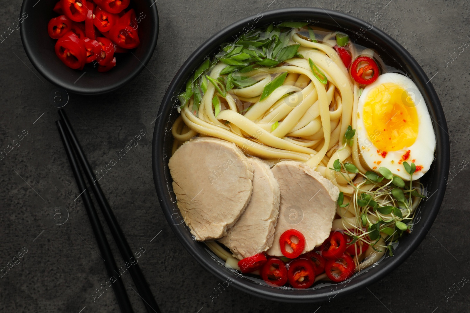 Photo of Delicious ramen with meat in bowl served on wooden table, flat lay. Noodle soup