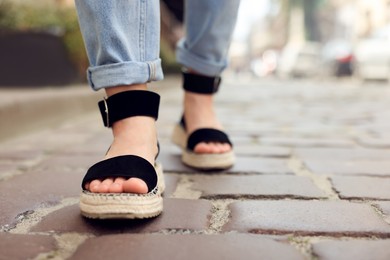 Photo of Woman in stylish sandals walking on city street, closeup. Space for text