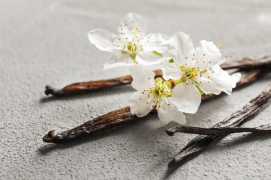 Vanilla sticks and flowers on light background