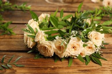 Photo of Composition with wreath made of beautiful flowers on wooden table, closeup
