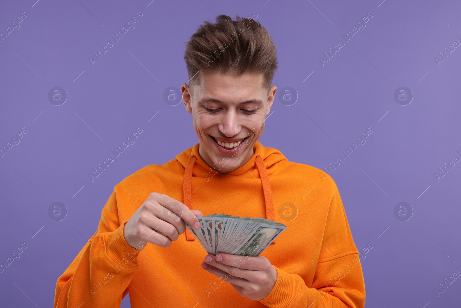 Photo of Happy man with money on purple background