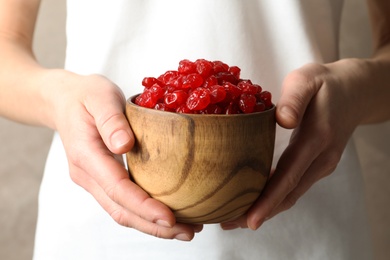 Photo of Woman holding bowl with tasty cherries on color background, closeup. Dried fruits as healthy food