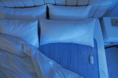 Photo of Bed with electric heating pad indoors at night