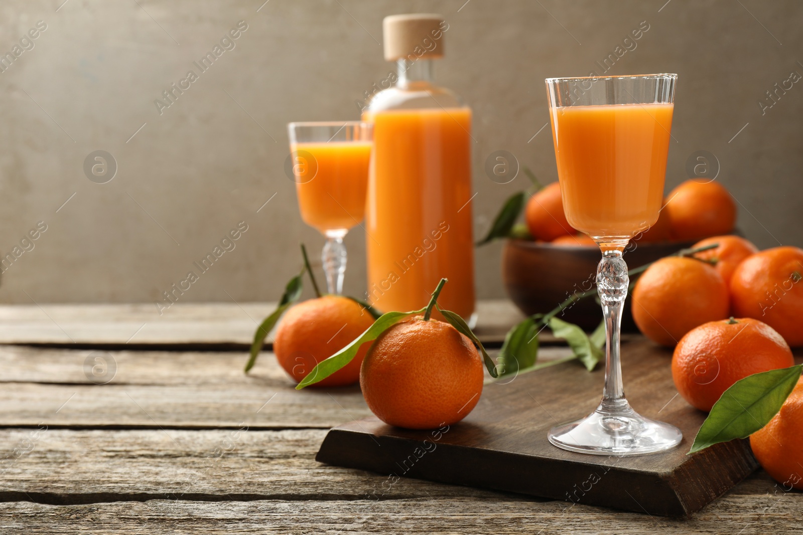 Photo of Delicious tangerine liqueur and fresh fruits on wooden table, space for text