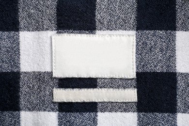 Photo of Blank clothing label on checkered shirt, top view