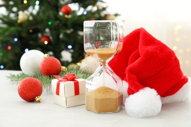 Hourglass with Santa hat and decor on table. Christmas countdown