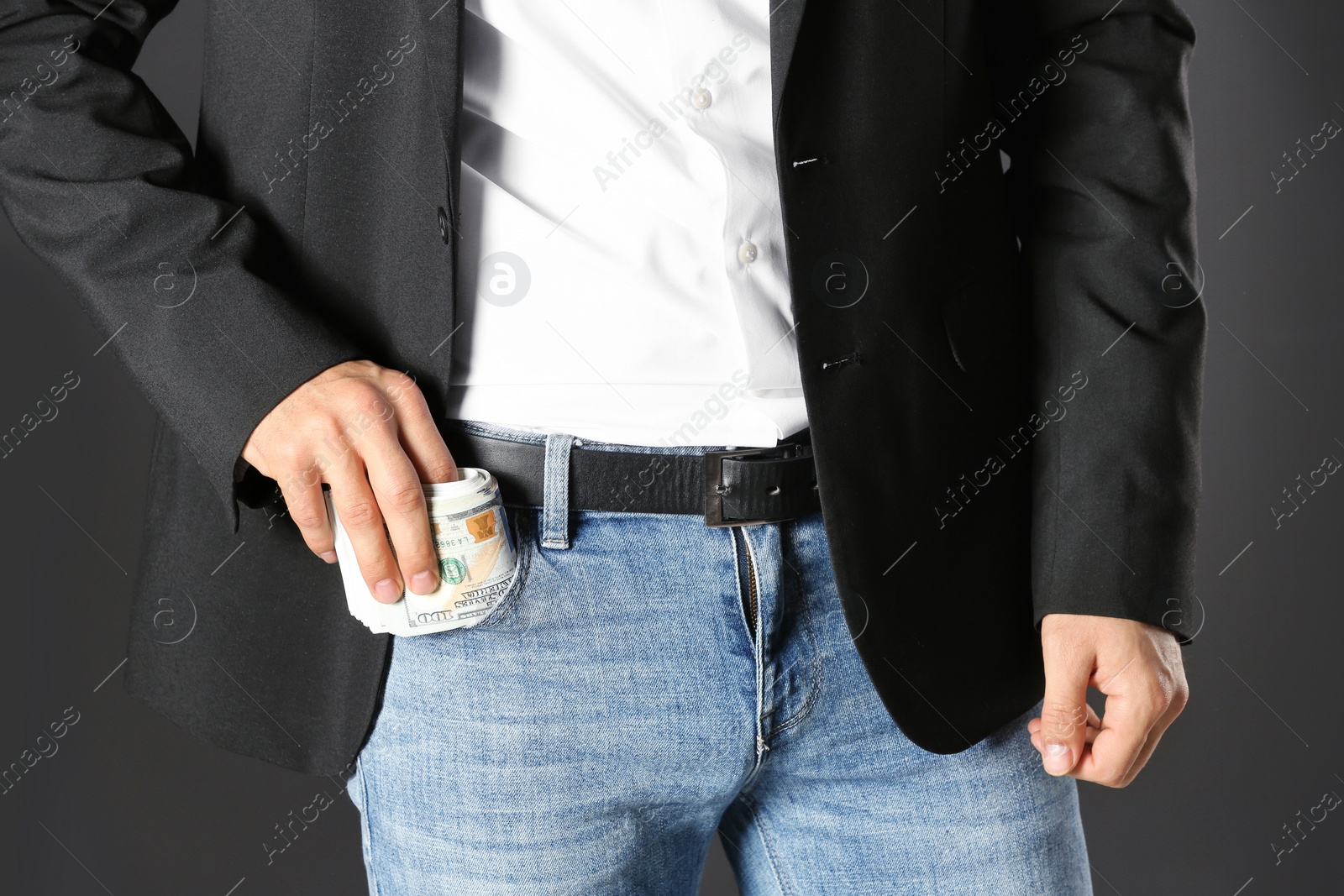 Photo of Man putting bribe money into pocket on black background, closeup