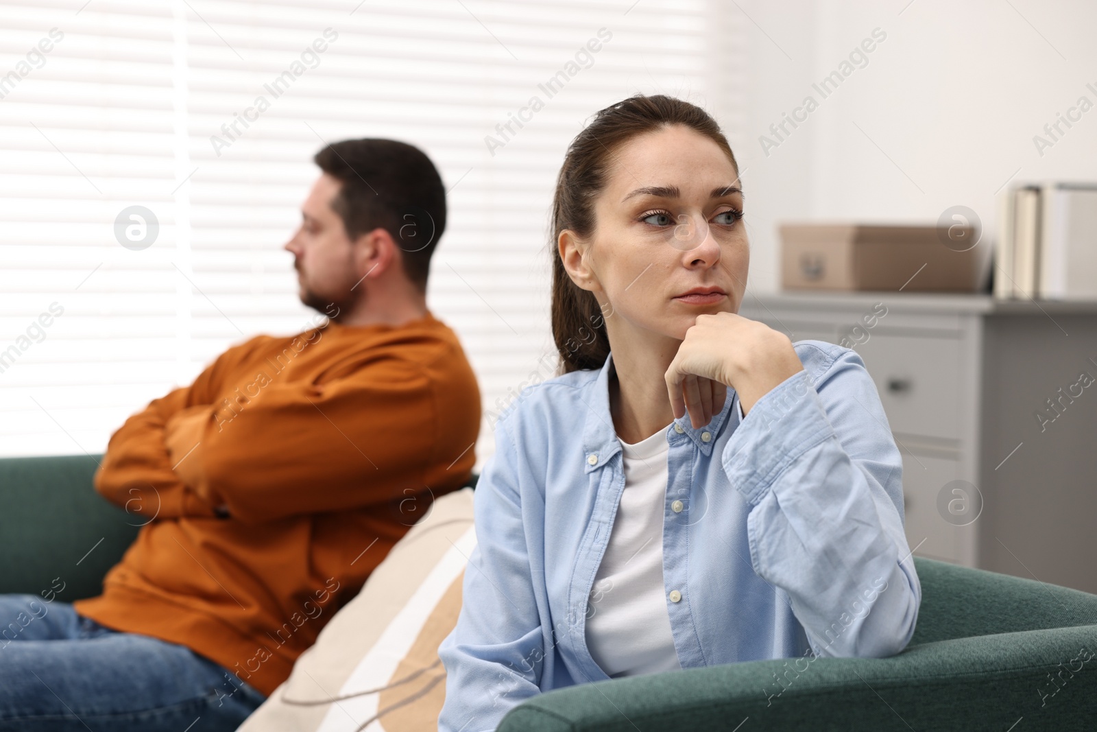 Photo of Offended couple ignoring each other after quarrel indoors, selective focus. Relationship problems