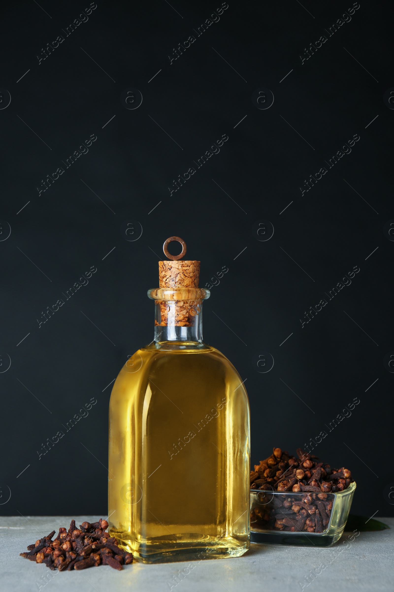 Photo of Essential oil and dried cloves on grey stone table