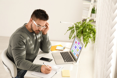 Young man using calendar app on laptop in office